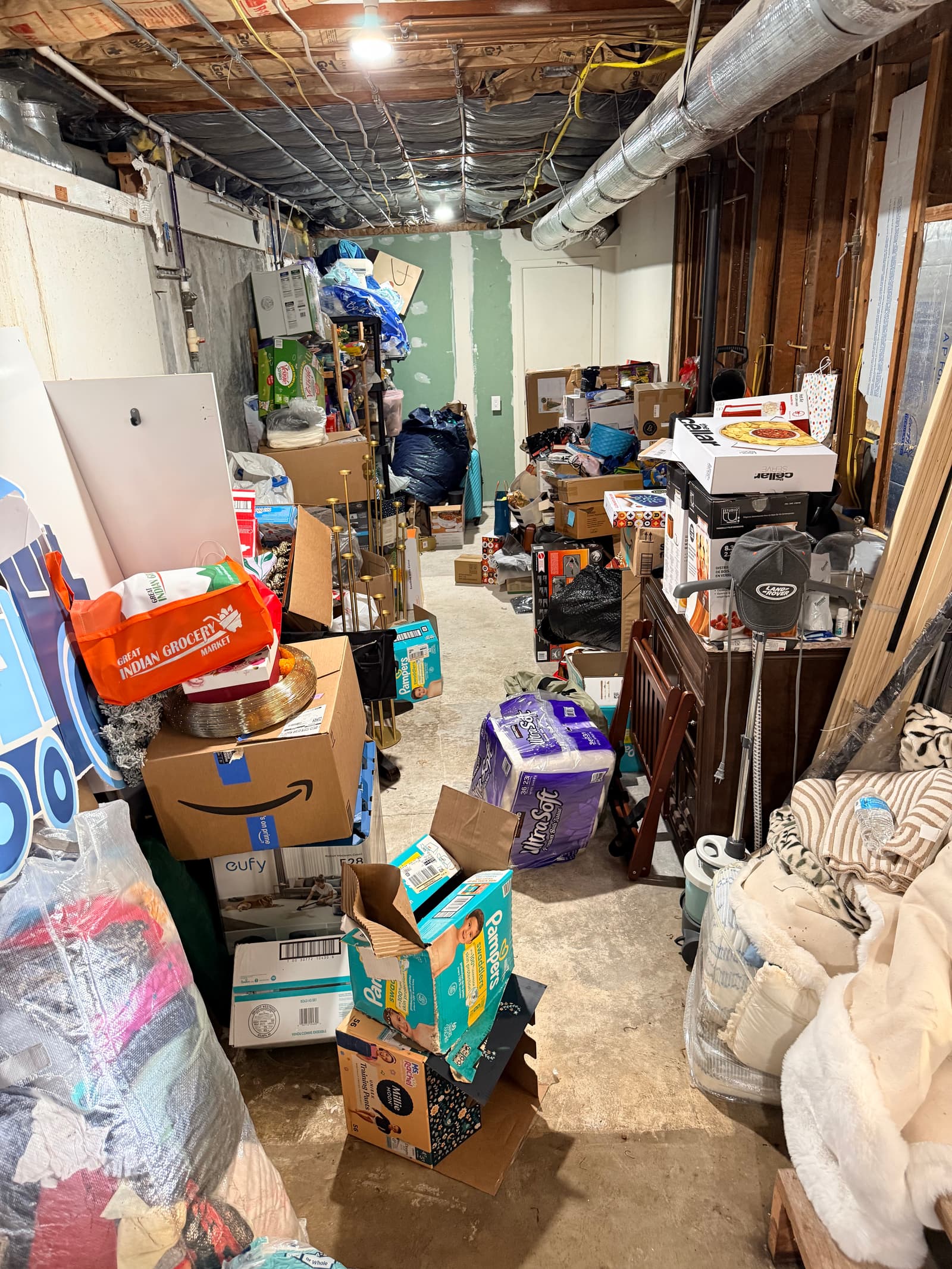 Basement hallway before: floor-to-ceiling boxes and bags with no room to walk