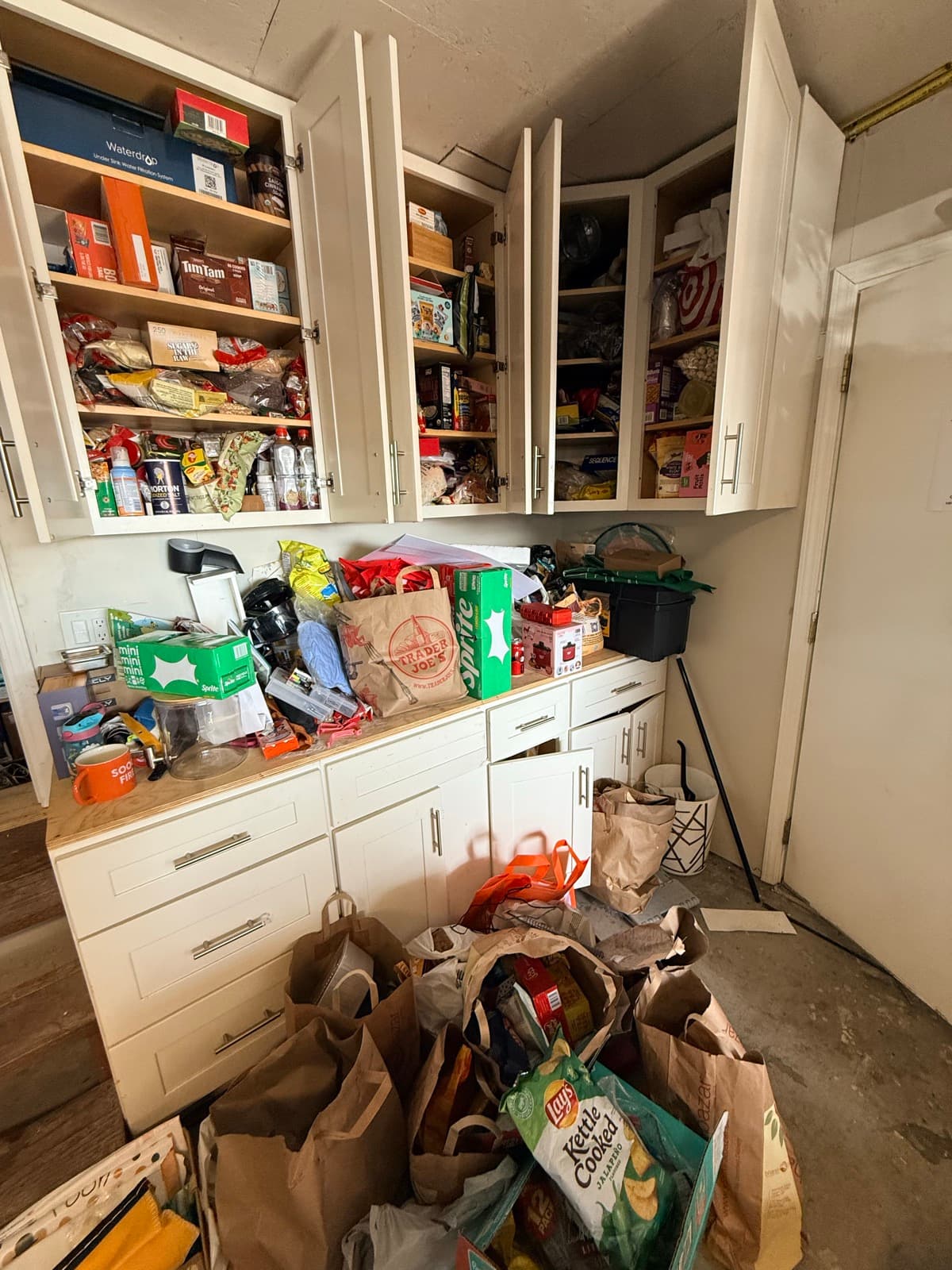 Pantry before: drawers open with spilling contents, counters covered in bags