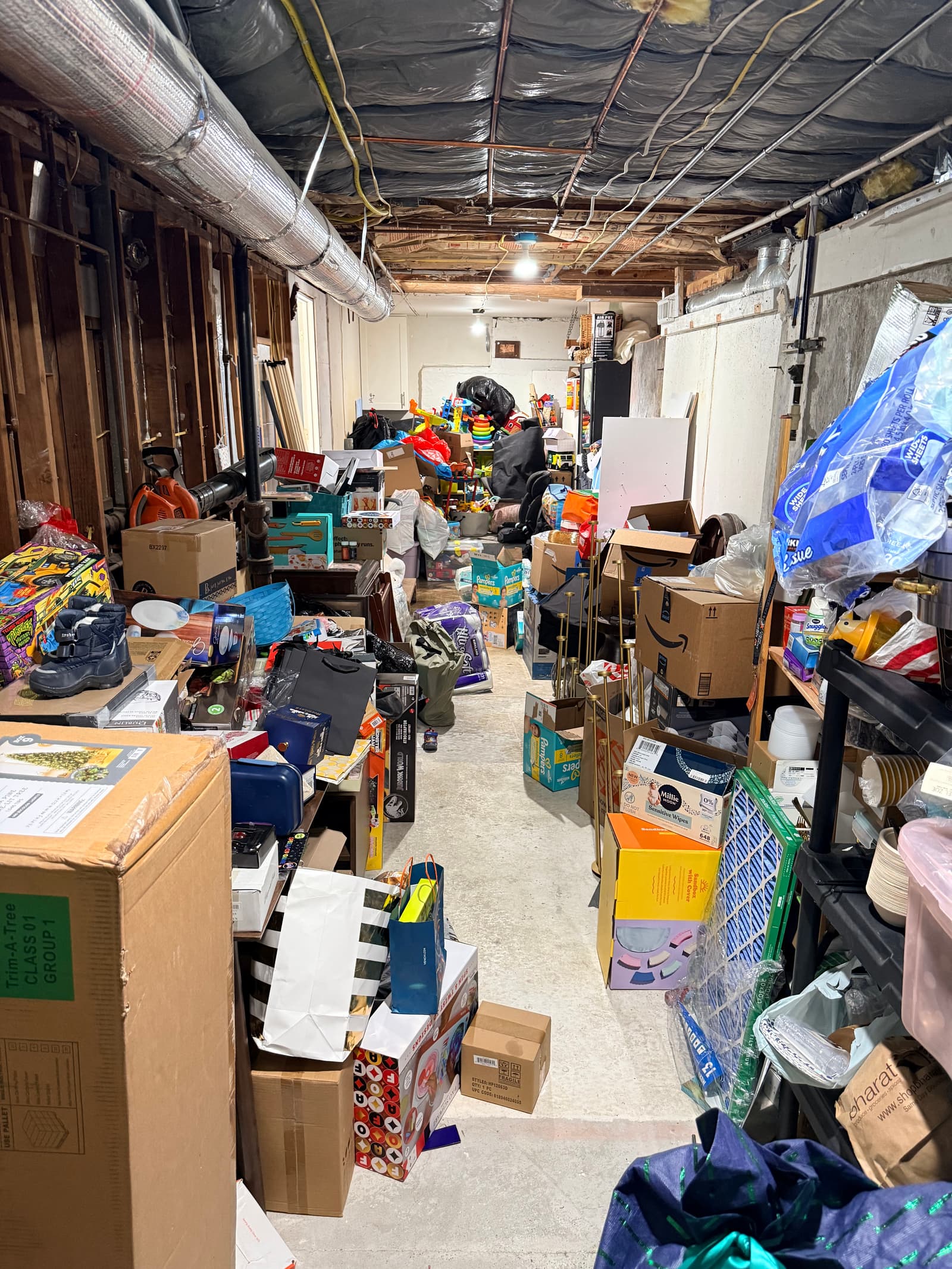 Basement hallway before (second angle): packed with boxes, Pampers, Amazon boxes stacked high